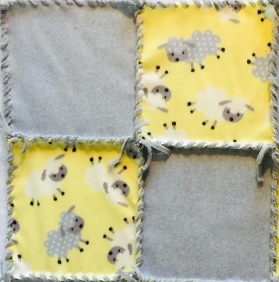 Fleece patchwork 24 inch blanket with gray and white sheep on light yellow with Solid gray squares and white fleece ribbon