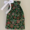4.5 x 7 inch cotton small drawstring gift bag with dark green background and red and pink flowers with light green leaves