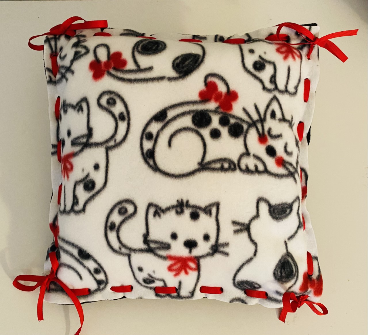 Kitten fleece pillow with white background and black sketched kittens with red bows