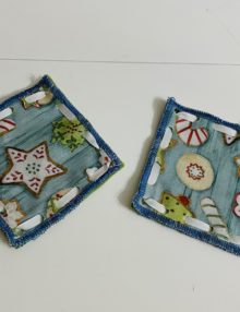 Set of 2 No sew 4.5 inch coasters with light blue background and white, red, green iced Christmas Cookie pattern