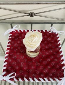 10 inch candle mat with Red and black houndstooth and small white snowflakes pattern, displayed with Scentsy Fragrence Flower sitting in center