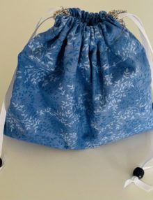 Ten inch drawstring bag with blue and white leaf pattern and small bead accents on white ribbon drawstrings