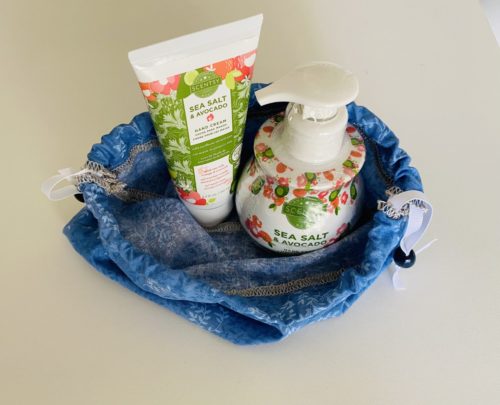 light blue drawstring bag opened up to show Scentsy Hand Soap and Scentsy Hand Lotion inside as gift accessory