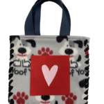 Fleece tote bag made with Gray fleece with White and Black dogs, red paw prints, and text saying I Woof You, on front is a 5 inch red pocket with pink heart