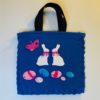 Royal blue 13 inch fleece tote bag with appliques on front of two white Easter Bunnies, colorful Easter Eggs, and Butterfly