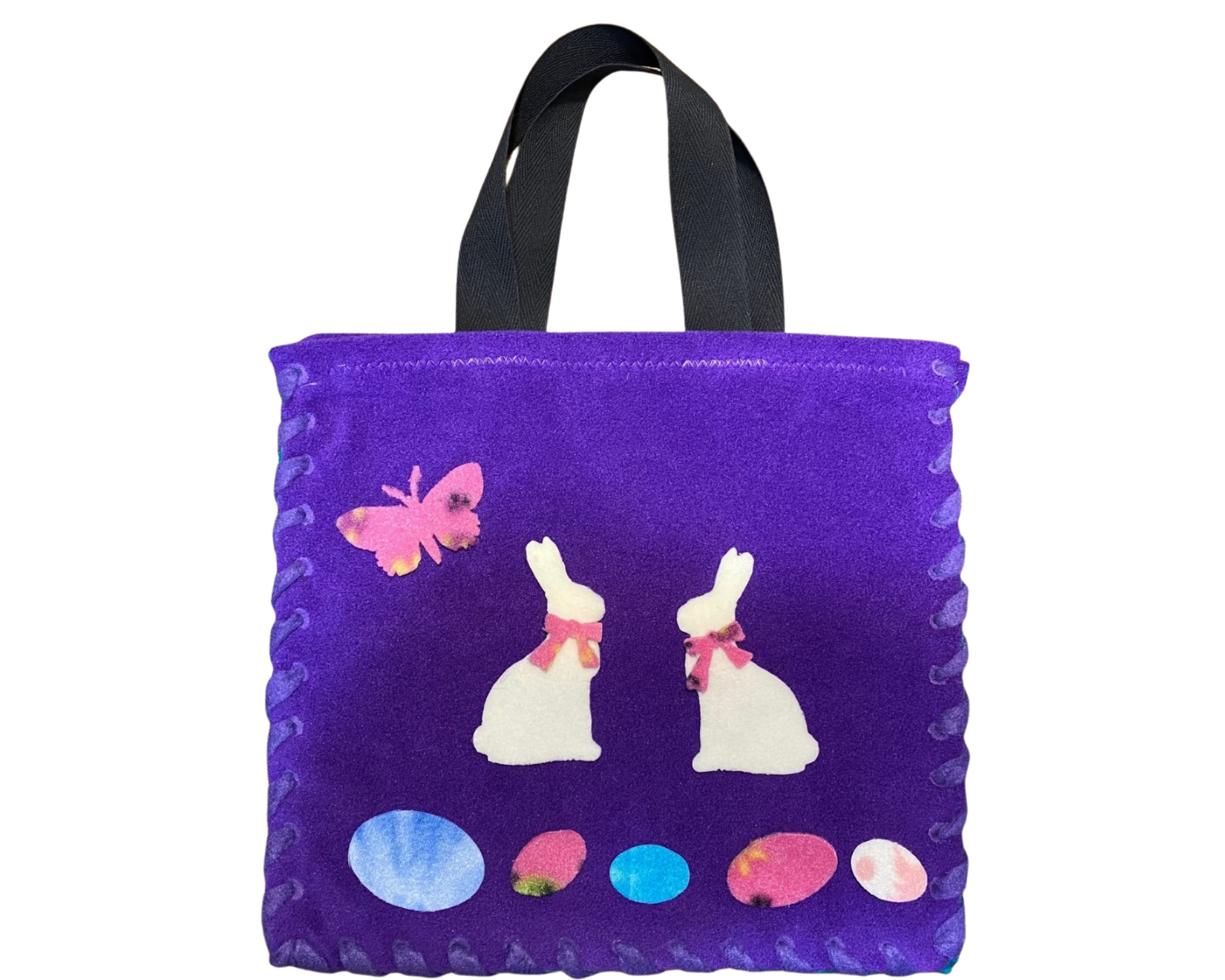 Vibrant purple fleece Easter tote with vibrant green lining, black tote straps, and appliques on front including two white bunnies, a multi colored butterfly and multicolored Easter Eggs displayed on front.
