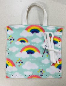 13" fleece tote bag in light teal with rainbows, clouds and small hearts, white tote straps, and white fleece ribbon to lace with plastic needle