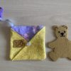 Pet in pocket pouch teddy bear beside pocket pouch in purple butterfly and yellow floral fabric.