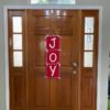 Red and White JOY Wall Hanging 30 inches by 10 inches with large white lettering and white running stitches with white ribbon