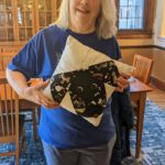 Merrilee Hill Kennedy holding her nine patch puppy dog face pillow she completed!